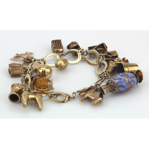 656 - 9ct / Yellow metal charm bracelet with a good variety of charms attached. Total weight 46.5g