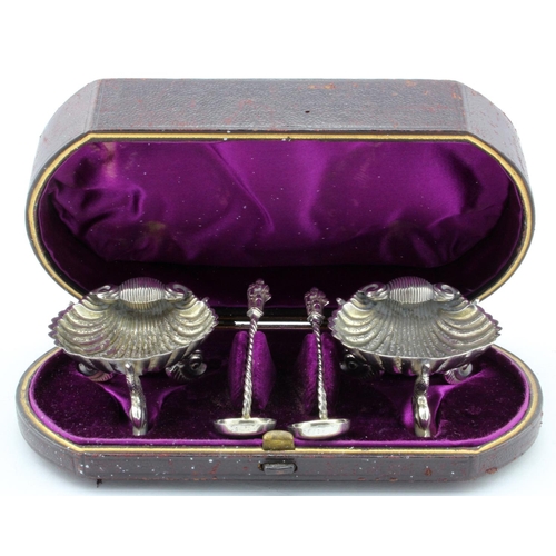 889 - Boxed set of two silver shell shaped salts, each standing on three dolphin feet + two Apostle type s... 