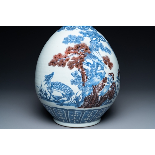 129 - A Chinese blue, white and copper-red bottle vase with a deer and birds among blossoming branches, 19... 