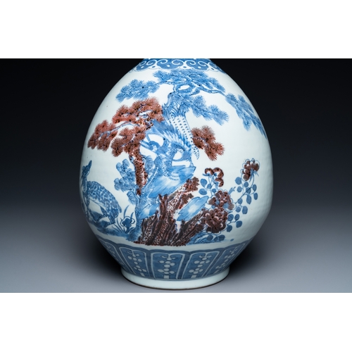 129 - A Chinese blue, white and copper-red bottle vase with a deer and birds among blossoming branches, 19... 