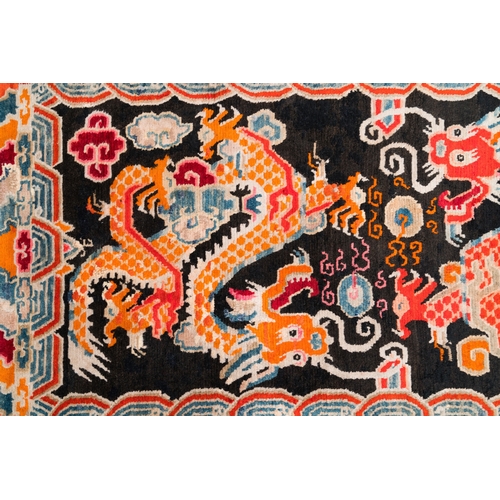 438 - A Tibetan rug with two dragons chasing the pearl of wisdom, 19th C.Dim.: 173,5 x 91,5 cm... 