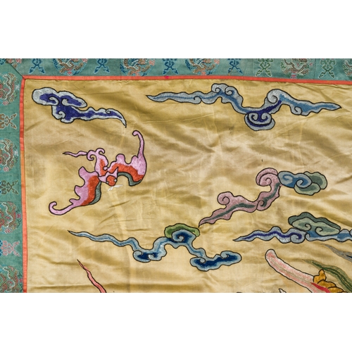 105 - A large Chinese yellow-ground silk embroidery decorated with three five-clawed dragons, 19th C.Descr... 