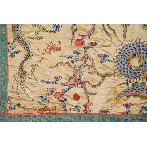 105 - A large Chinese yellow-ground silk embroidery decorated with three five-clawed dragons, 19th C.Descr... 