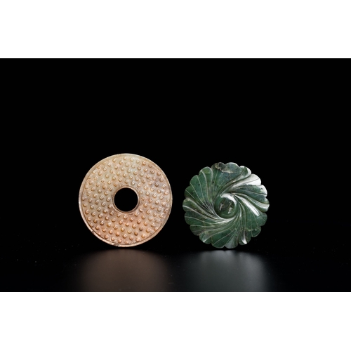 470 - A Chinese celadon and russet jade 'bi' disc and a spinach green flower-shaped pendant on wooden stan... 