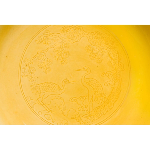 166 - A pair of Chinese monochrome yellow-glazed saucers with incised designs of pine and cranes, Yongzhen... 