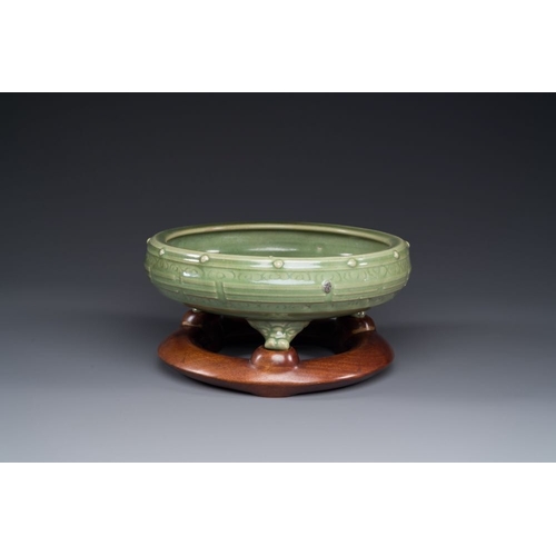 383 - A Chinese Longquan celadon tripod censer on wooden stand, Yuan/MingDia.: 31 cm - H.: 15 cm (incl. st... 