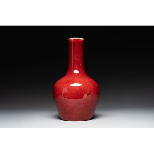 406 - Two Chinese monochrome copper-red-glazed bottle vases on wooden stands, 19th C.H.: 42,5 cm (the larg... 