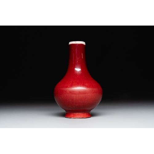 406 - Two Chinese monochrome copper-red-glazed bottle vases on wooden stands, 19th C.H.: 42,5 cm (the larg... 