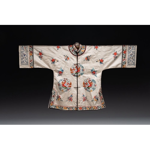 1057 - Two Chinese embroidered silk women's robes, 19/20th C.Dim.: 131,5 x 79,5 cm (the white robe)Dim.: 13... 