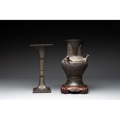 762 - A Chinese archaistic bronze 'gu' vase and a 'hu' vase with rams in relief on a wooden stand, 18/19th... 