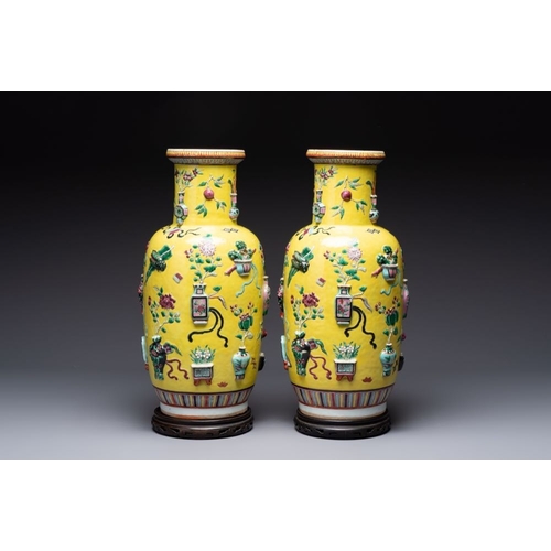 25 - A pair of Chinese famille rose yellow-ground relief-decorated vases with wooden stands, 19th C.H.: 4... 