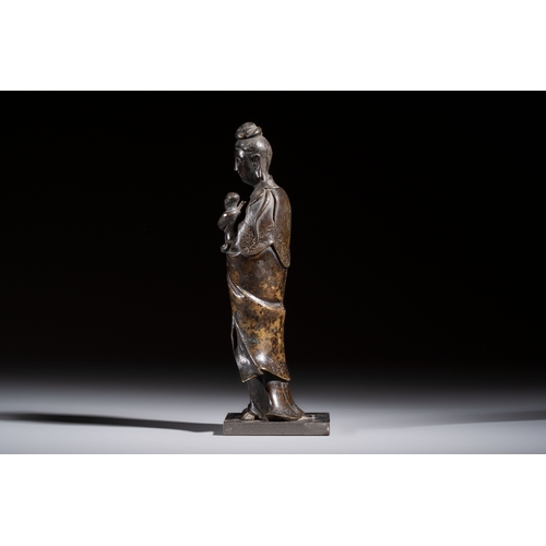 260 - A Chinese bronze standing Guanyin with boy, MingH.: 20,7 cm (incl. stand)H.: 19,7 cm (excl. stand)
W... 