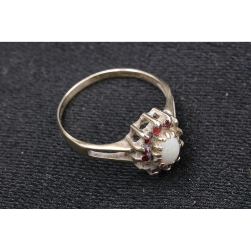 94 - 9 CT Gold Ladies Ring with an Opal Centre Stone with small red stones surrounding it, 1 missing. Ove... 