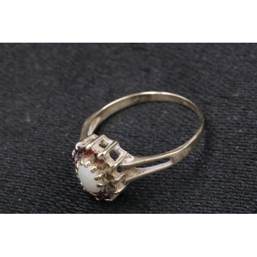 94 - 9 CT Gold Ladies Ring with an Opal Centre Stone with small red stones surrounding it, 1 missing. Ove... 