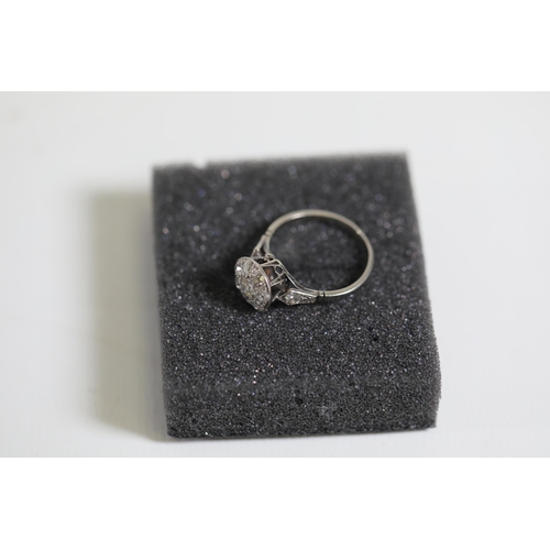 111 - A diamond cluster ring, with diamond shoulders, set in Platinum, ring size Q