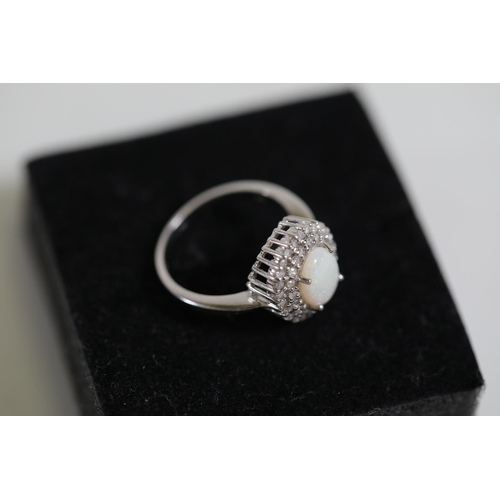 113 - An Oval white opal an diamond cluster ring, set in 9ct white gold, ring size O