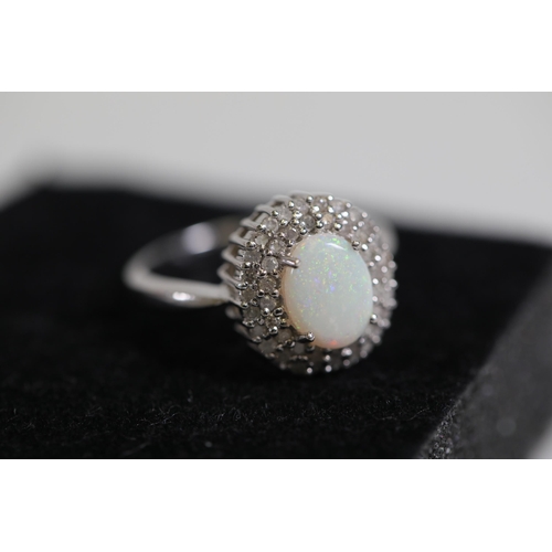 113 - An Oval white opal an diamond cluster ring, set in 9ct white gold, ring size O