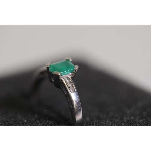 124 - An emerald solitaire ring with diamond shoulders, set in 9ct white gold, ring size O-P