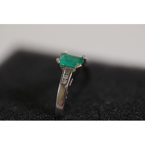 124 - An emerald solitaire ring with diamond shoulders, set in 9ct white gold, ring size O-P