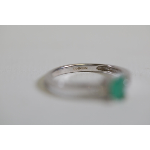 124 - An emerald solitaire ring with diamond shoulders, set in 9ct white gold, ring size O-P