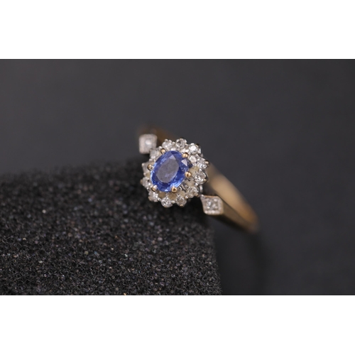 37 - Oval sapphire in diamond cluster set in 9ct yellow gold with diamond shoulders Ring size between N a... 