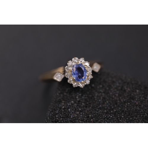 37 - Oval sapphire in diamond cluster set in 9ct yellow gold with diamond shoulders Ring size between N a... 