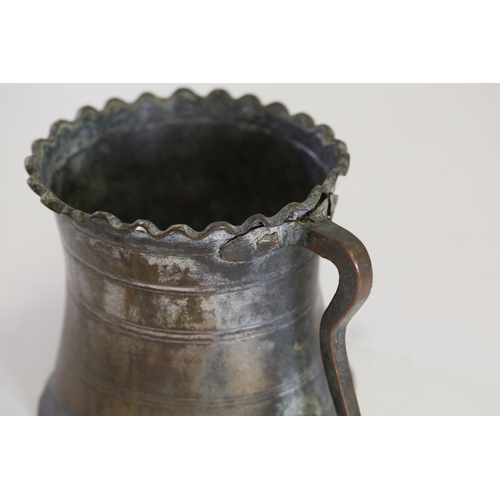 18 - An antique Middle Eastern bath pitcher made of bronze or copper, featuring a flared base, a wavy top... 