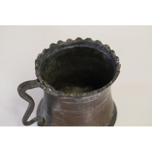 18 - An antique Middle Eastern bath pitcher made of bronze or copper, featuring a flared base, a wavy top... 