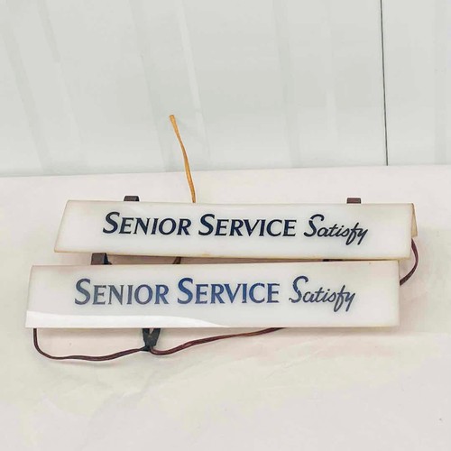 Two 'Senior Service Satisfy' signs, vintage style, with electrical wiring.