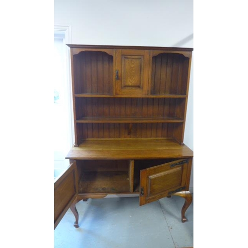 134 - An oak dresser, plate rack over base of two doors raised on cabriole supports - 129cm x 50cm x 191cm... 