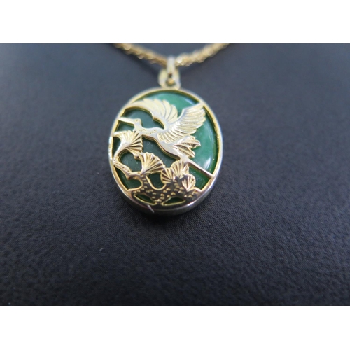 870 - An 18ct yellow gold necklace with a Jade and gold pendant - the pendant decorated with bird amongst ... 