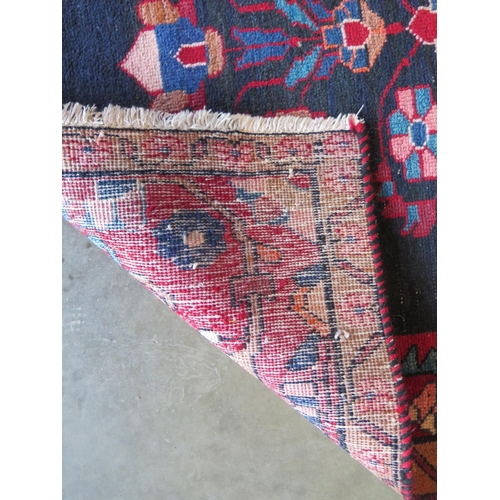 479 - A hand knotted woollen rug with a red field, generally good, some small wear - 204cm x 112cm