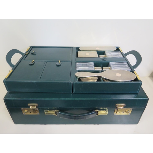 607 - A good quality green leather travel case with a fitted inner case having two silver brushes, three b... 