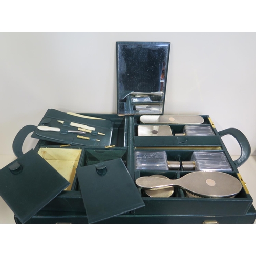 607 - A good quality green leather travel case with a fitted inner case having two silver brushes, three b... 