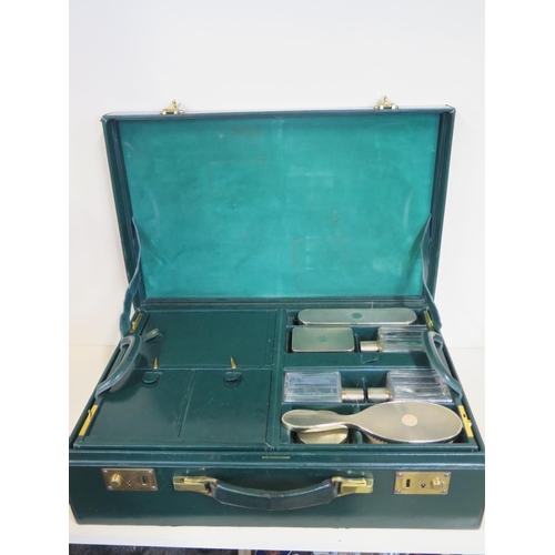 607 - A good quality green leather travel case with a fitted inner case having two silver brushes, three b... 