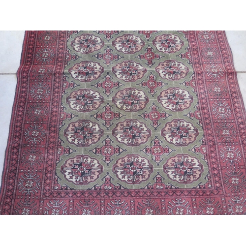 458 - A woollen rug decorated with medallions on a central green field with red borders and flat weave end... 