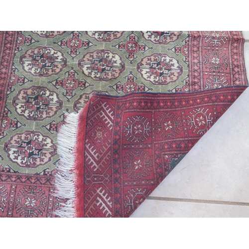 458 - A woollen rug decorated with medallions on a central green field with red borders and flat weave end... 