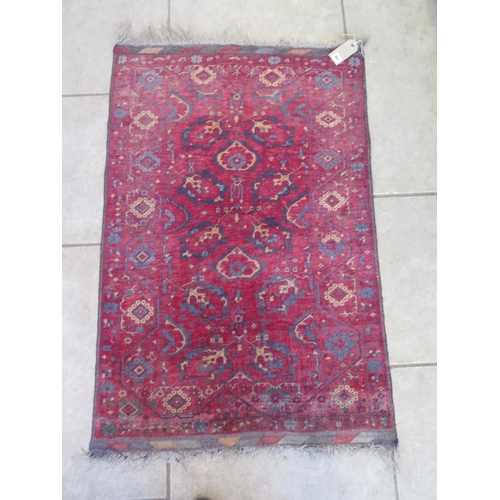 491 - A hand knotted woollen rug with a red field - 137cm x 84cm - some usage wear mainly to edges but no ... 