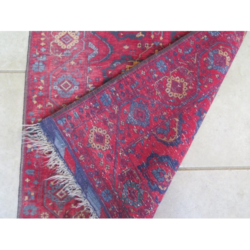 491 - A hand knotted woollen rug with a red field - 137cm x 84cm - some usage wear mainly to edges but no ... 