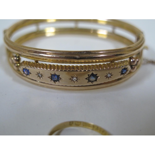 657 - A 9ct gold bangle with diamonds, a sapphire and three blue stones, approx 11.3 grams, approx 6.5cm o... 