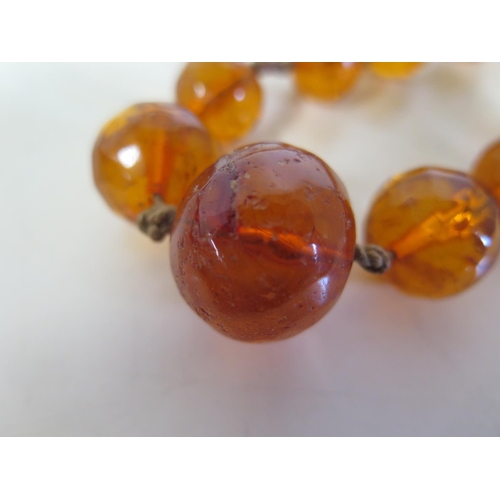 694 - A string of amber type beads, 120cm long, largest bead 2.5cm x 2cm - total weight approx 88 grams