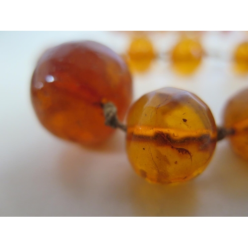 694 - A string of amber type beads, 120cm long, largest bead 2.5cm x 2cm - total weight approx 88 grams