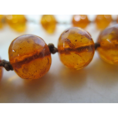 694 - A string of amber type beads, 120cm long, largest bead 2.5cm x 2cm - total weight approx 88 grams