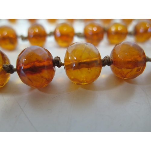 694 - A string of amber type beads, 120cm long, largest bead 2.5cm x 2cm - total weight approx 88 grams