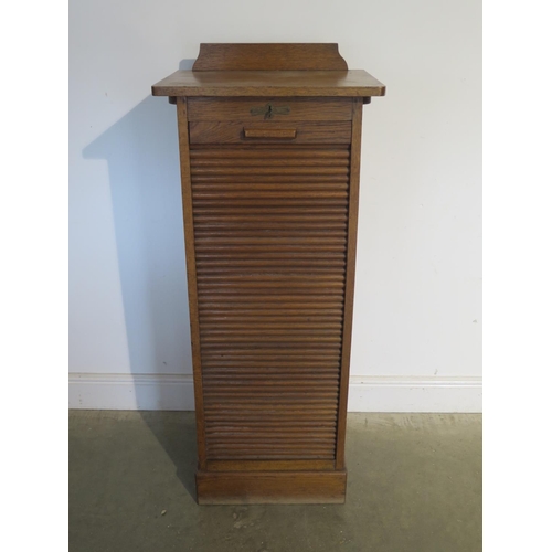 253 - An early 1900s oak filing storage cabinet with a tambour front enclosing nine slides, generally good... 