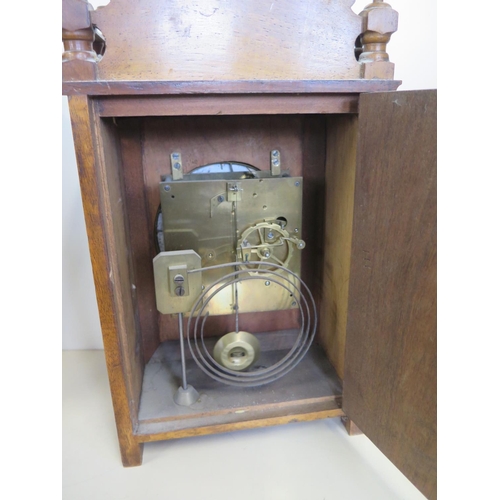 410 - A walnut mantle clock with a decorative dial, 36cm tall, striking on a gong, ticks but stops