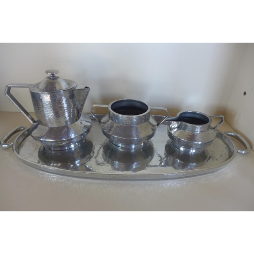 1250 - An early 20th century Warwick pewter hand hammered Arts and Crafts three piece tea/coffee set with o... 