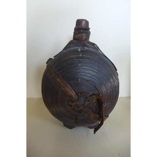 1242 - A carved moon shaped wooden flask, 26cm tall, with remains of leather strapping, general wear and cr... 