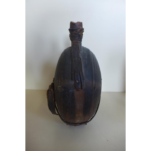 1242 - A carved moon shaped wooden flask, 26cm tall, with remains of leather strapping, general wear and cr... 