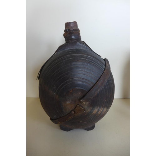 1242 - A carved moon shaped wooden flask, 26cm tall, with remains of leather strapping, general wear and cr... 